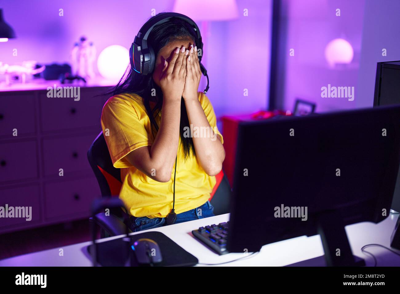 Eine junge, wunderschöne latina-Frau, die gestresst mit dem Computer im Spielzimmer spielte Stockfoto