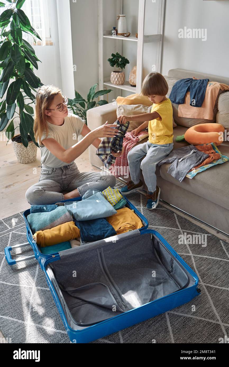 Familienmutter und -Kind, die zusammen einen Koffer packen, um eine Reise oder Urlaub zu machen Stockfoto