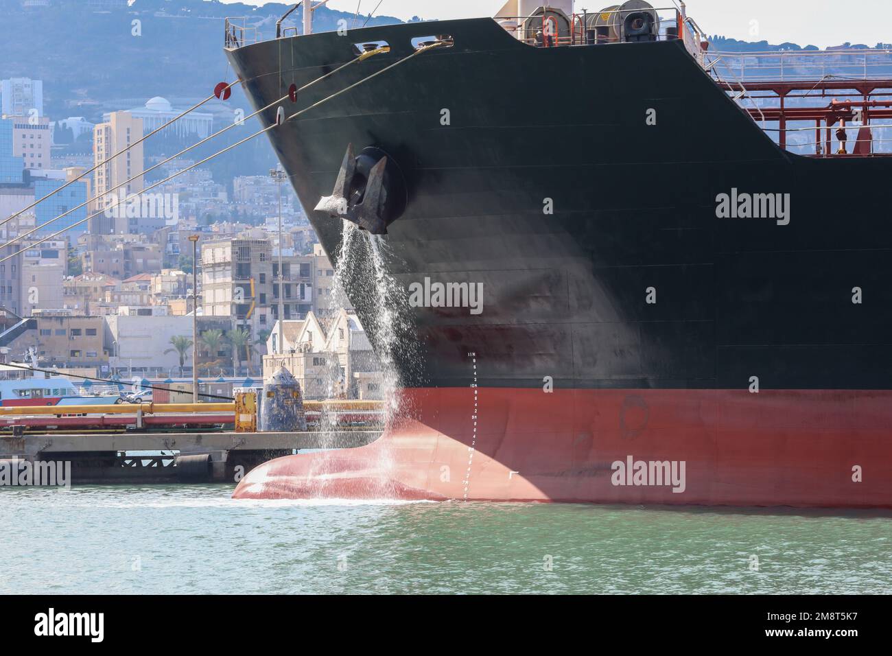 Großes, verankertes Frachtschiff, das Ballastwasser aus Anchors Hub ableitet. Stockfoto