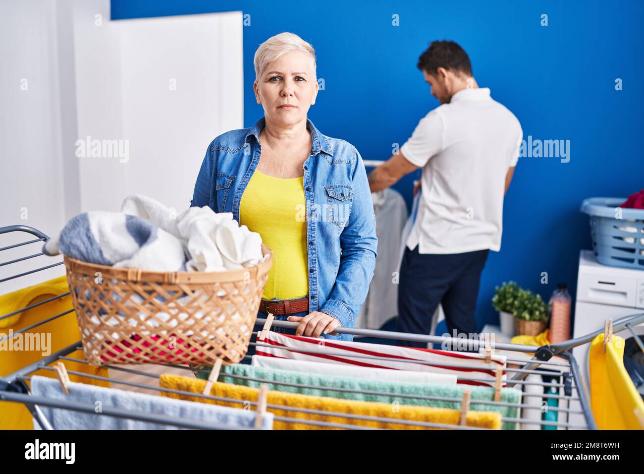 Hispanische Mutter und Sohn hängen Kleider an der Wäscheleine, denken und nüchtern aussehen selbstbewusst Stockfoto