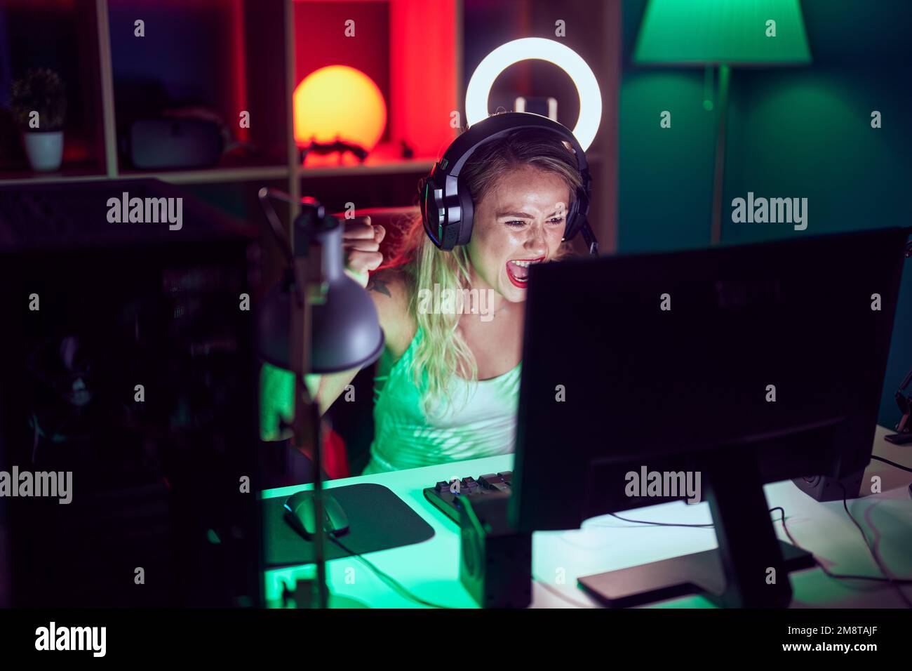 Junge schöne hispanische Frau streamer spielen Videospiel mit Sieger Ausdruck in Gaming-Raum Stockfoto