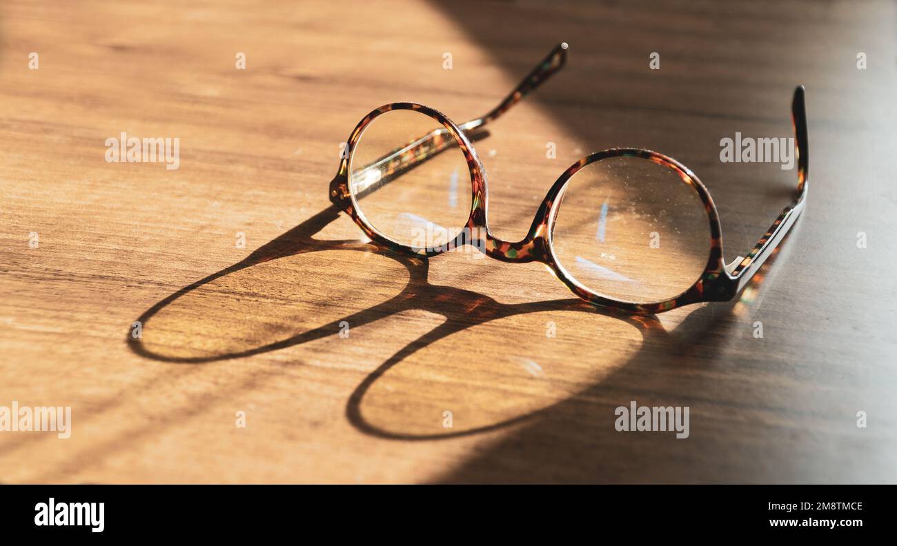 Gläser auf Holztisch. Sonnenschein auf Vintage-Gläsern auf dem Tisch. Weisheitskonzept. Platz für Text kopieren Stockfoto