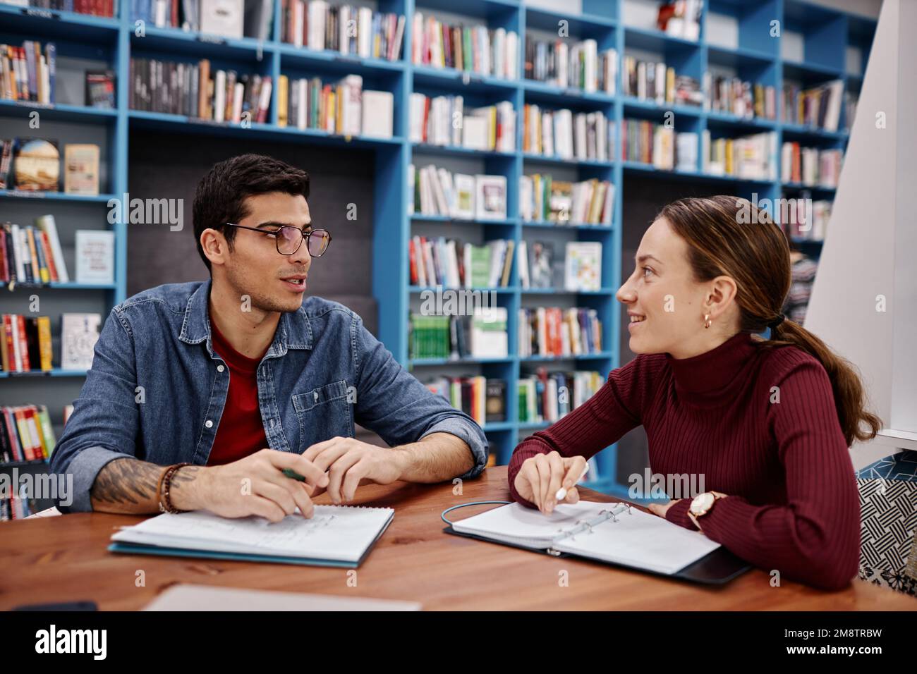 Porträt von zwei lächelnden jungen Menschen, Junge und Mädchen, die zusammen in der Collegebibliothek studieren Stockfoto