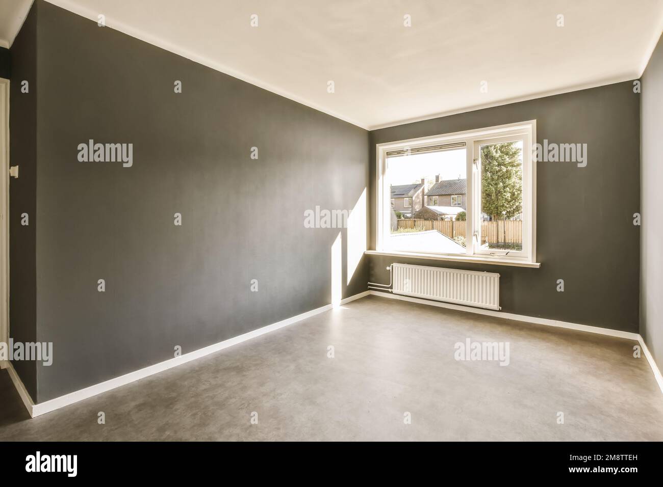 Ein leeres Wohnzimmer mit dunkelgrauen Wänden und weißen Verzierungen an den Wänden, es gibt ein radiales Fenster Stockfoto