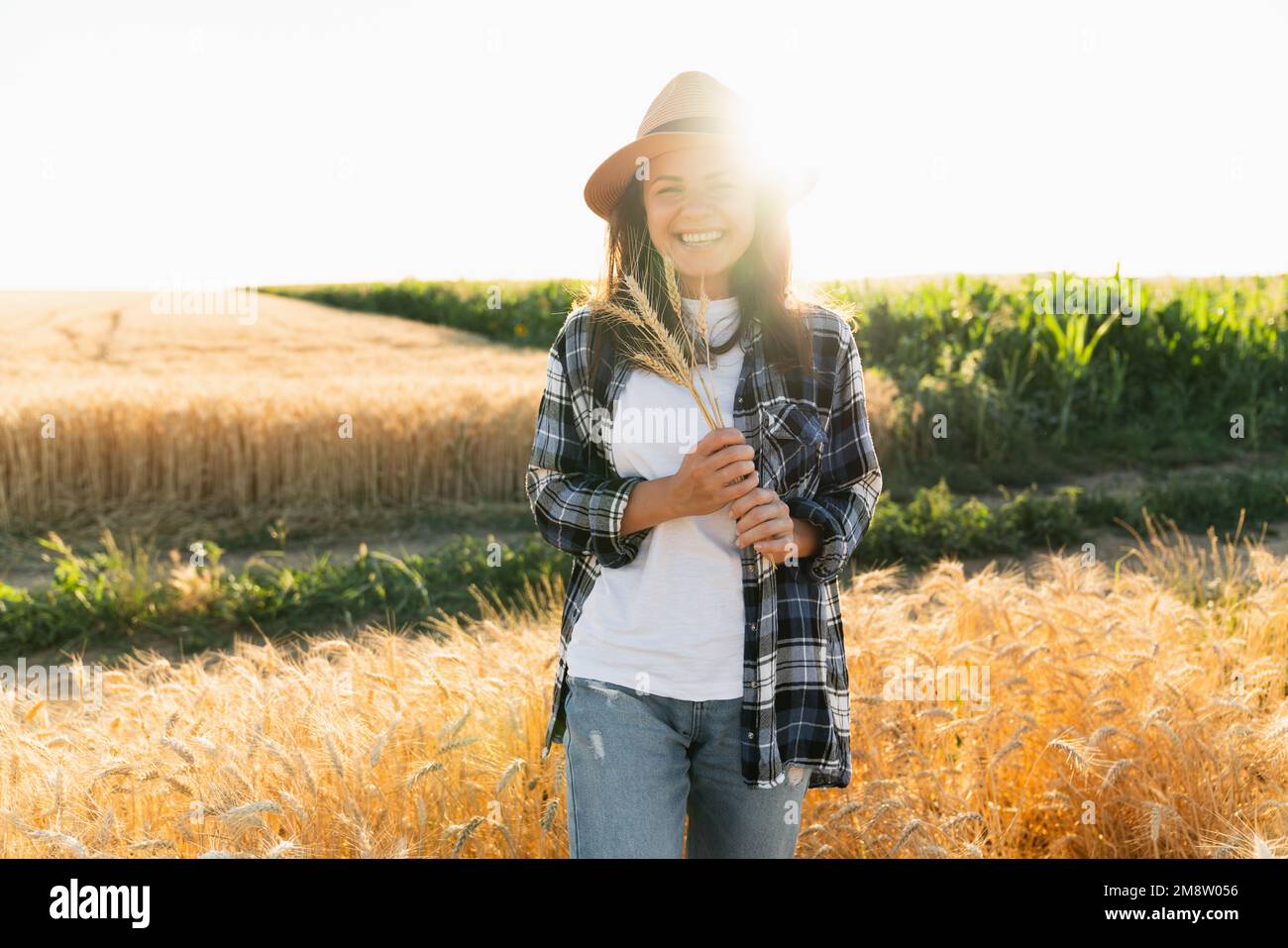 Porträt einer Frau mit Hut vor dem Hintergrund eines Sonnenuntergangsfeldes Stockfoto