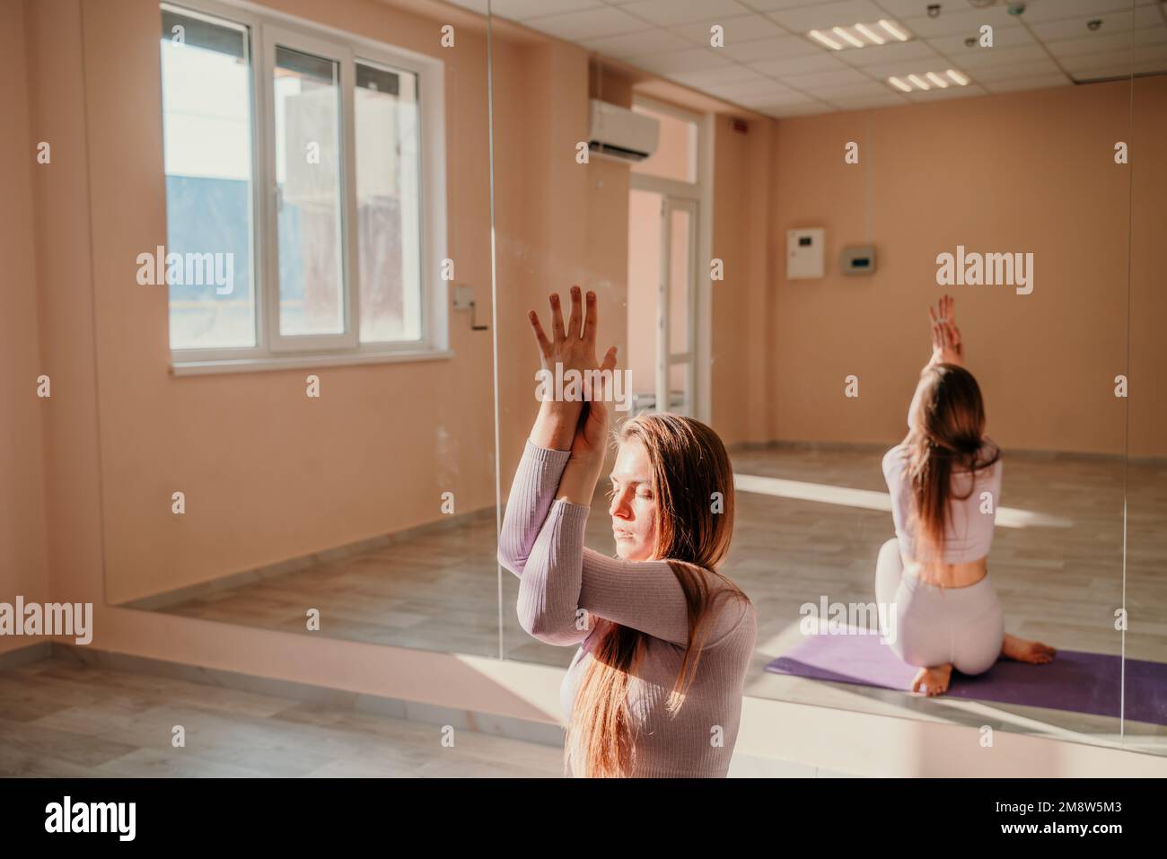 Blick von oben. Eine schöne junge Frau in pinkfarbener Sportbekleidung ist Yoga und Sport im Flur auf einem lila Teppich. Yoga, Sport und gesundes Konzept. Stockfoto