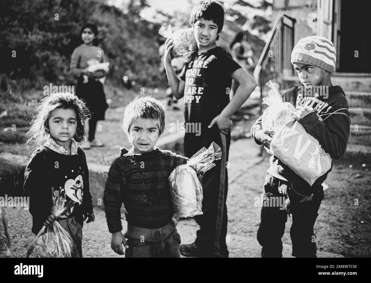 Ein Schwarzweißfoto der armen Kinder in einem rumänischen Höllenloch, das ihre Geschenktüten in der Hand hält Stockfoto