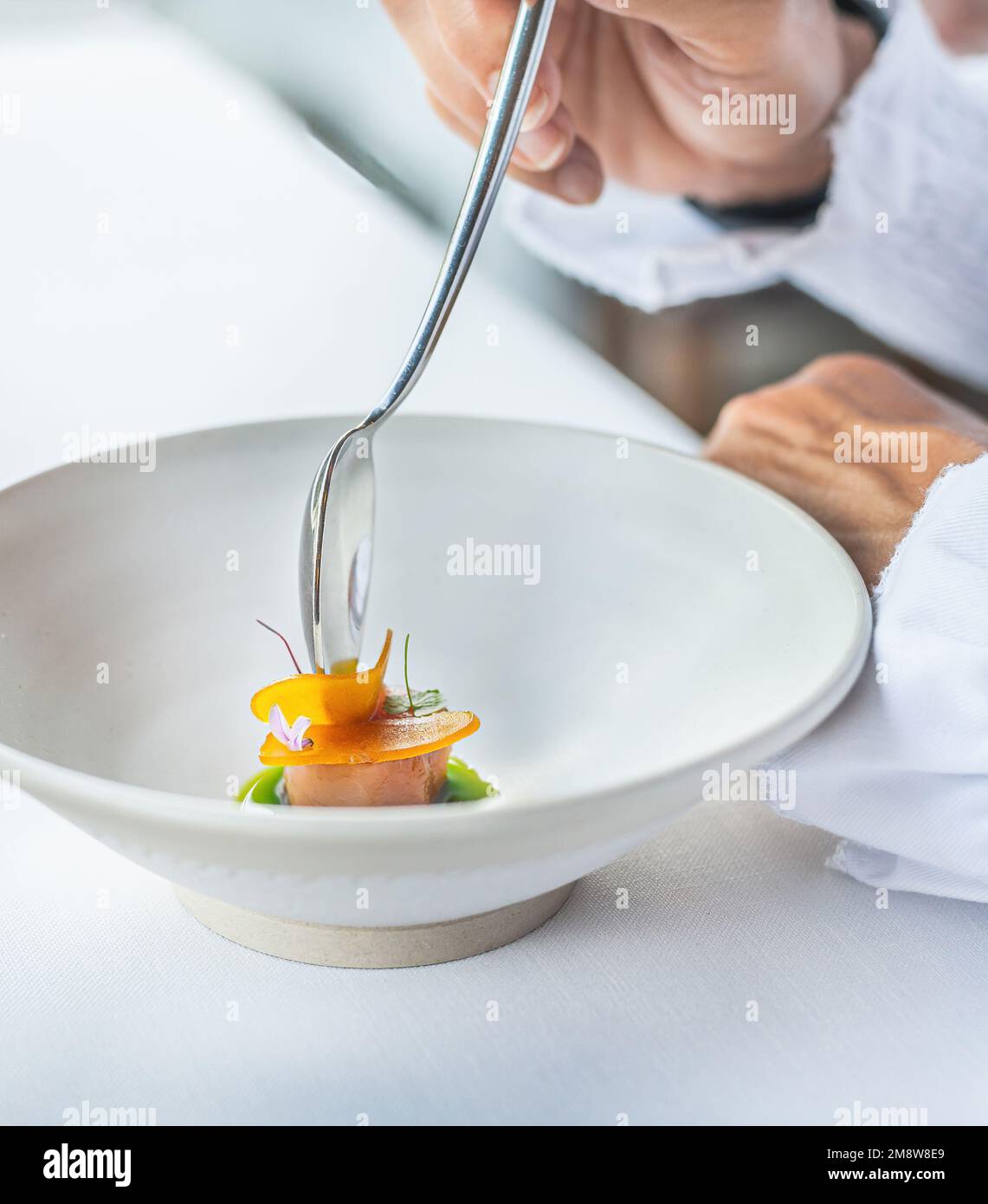 Detail einer Person, die ein Haute Cuisine-Rezept auf der Grundlage von Thunfisch in Kräuteröl probiert. Gourmet-Food-Konzept Stockfoto