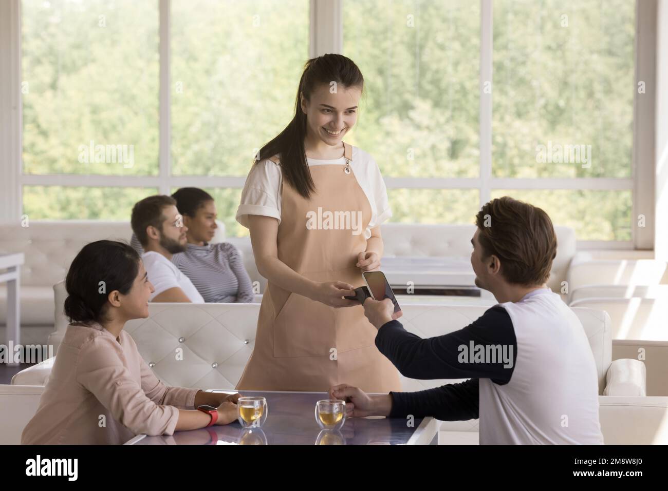 Fröhlicher junger Mann und Frau, die Rechnungen im Café bezahlen Stockfoto