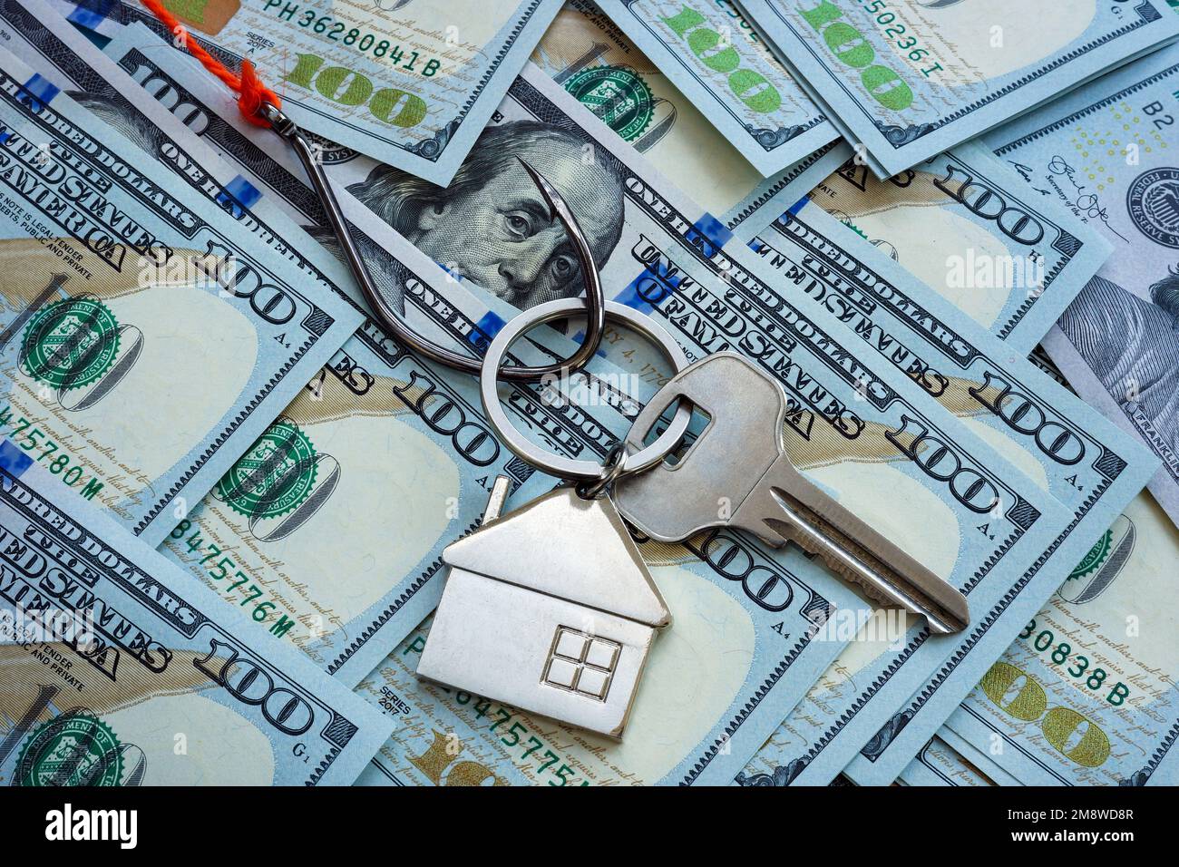 Das Konzept des Immobilienbetrugs. Der Haken und der Schlüssel zum Haus liegen auf dem Geld. Stockfoto