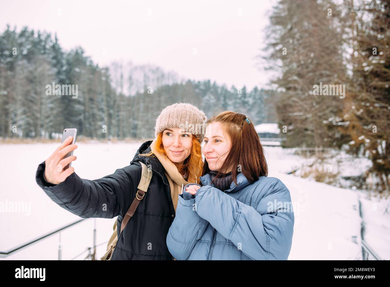 Zwei Frauen, die im Winter mit einem Telefon befreundet sind, machen im Winter ein Selfie Stockfoto