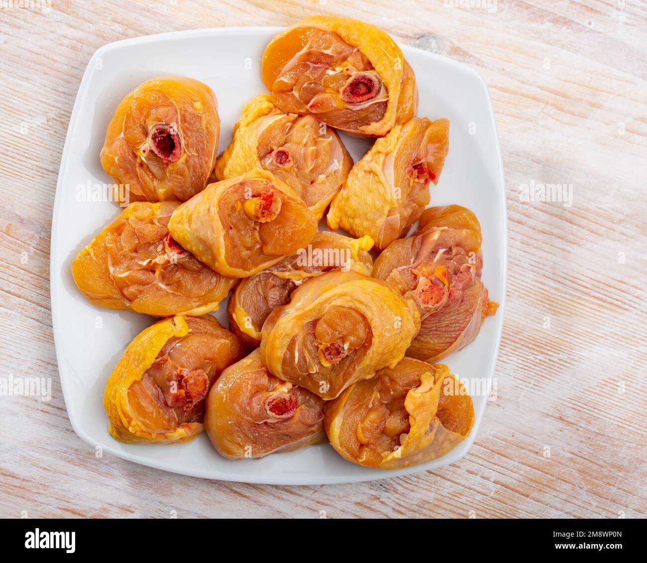 Bild von frischen, rohen Hähnchenschenkeln auf einer Holzfläche Stockfoto