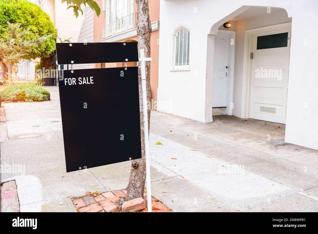 Nahaufnahme eines Immobilienschilds auf dem Gehweg vor einem verkauften Haus Stockfoto