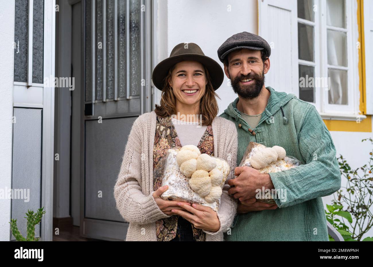 Süßes Bauernpaar mit Löwenmane-Pilzen in der Hand Stockfoto