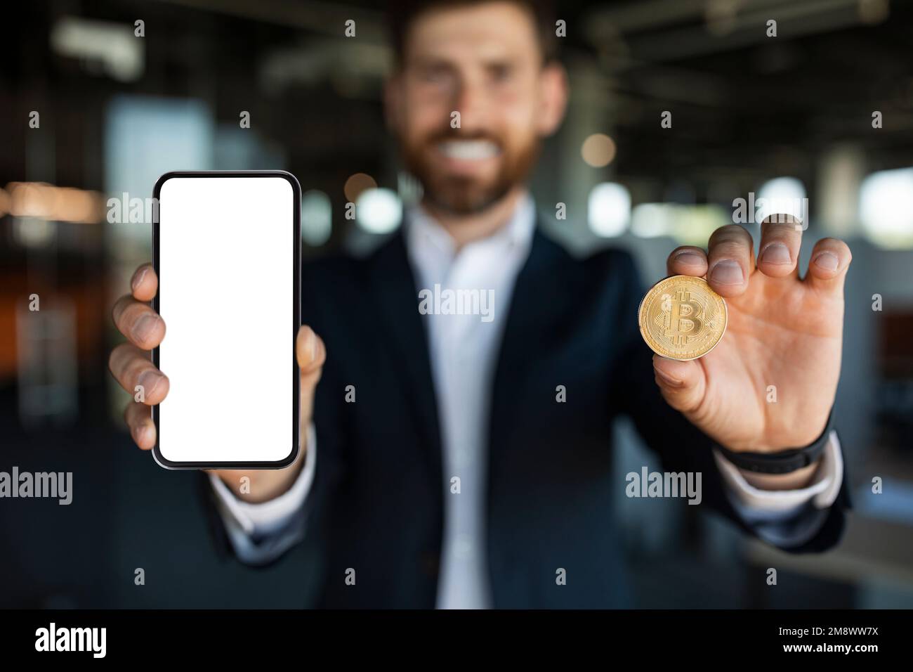 Kryptowährung-App. Glücklicher Geschäftsmann, der eine goldene Bitcoin und ein Smartphone mit leerem Bildschirm und Modell zeigt Stockfoto