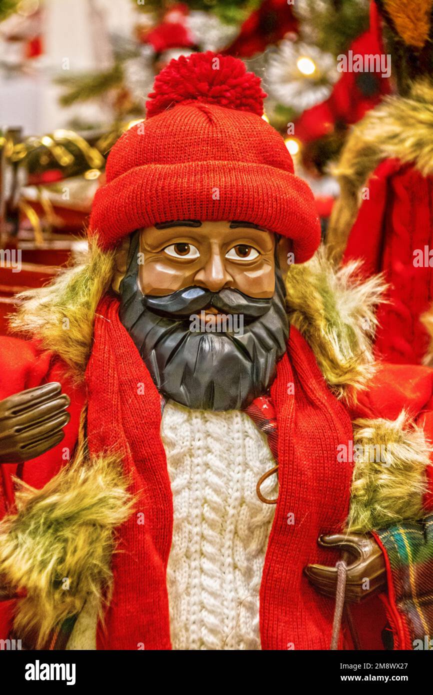 Dunkel gehäutete weihnachtsmann-Puppe aus Holz mit schwarzem Bart, Pullover mit Zopfmuster, roter Strumpfkappe und Mantel mit Fell Stockfoto