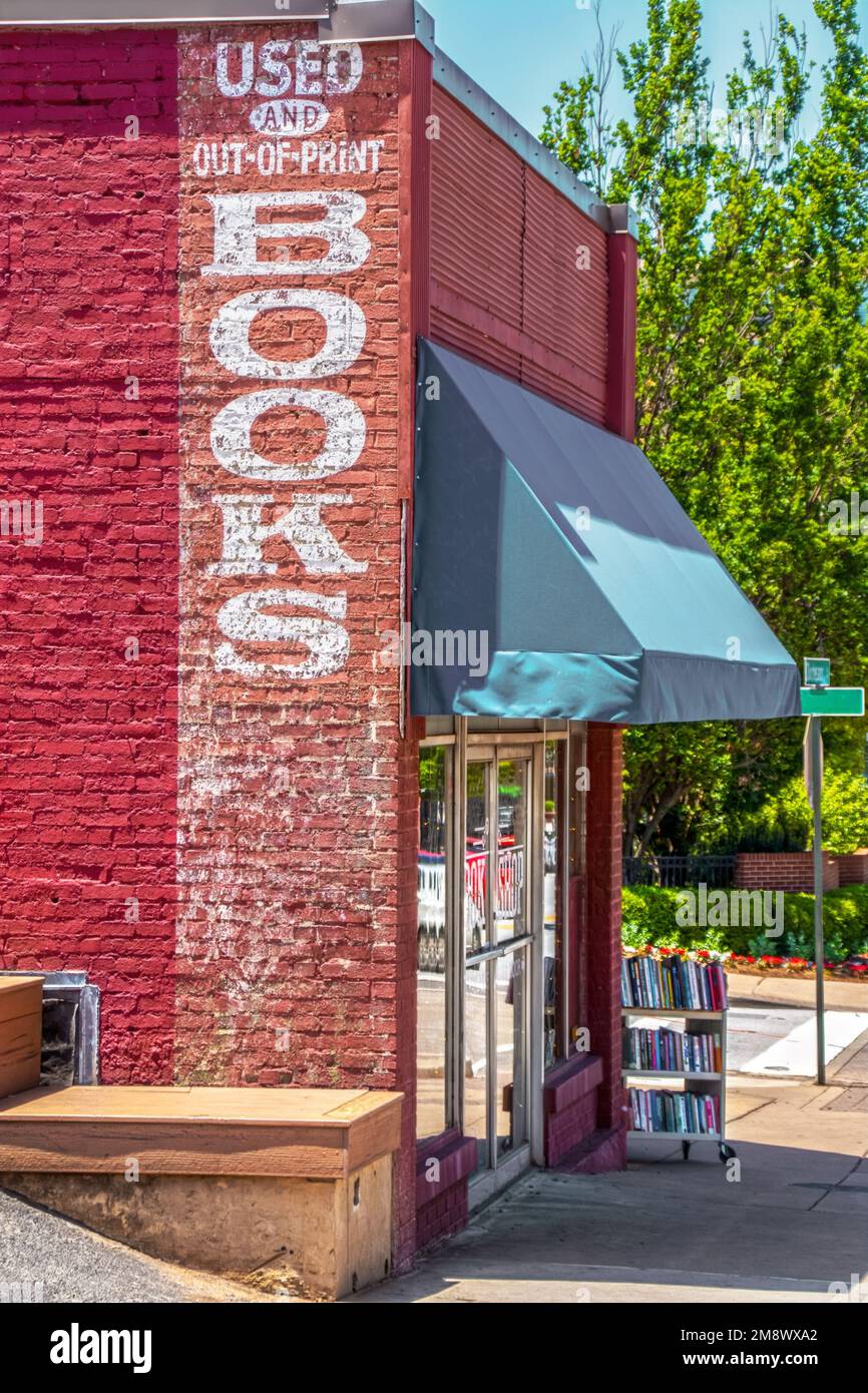 Gebrauchtbuchladen im Vintage-Stil: Gebrauchte und vergriffene Bücher, die auf Ziegelstein gemalt sind, und rollender Wagen mit Büchern auf dem Bürgersteig Stockfoto
