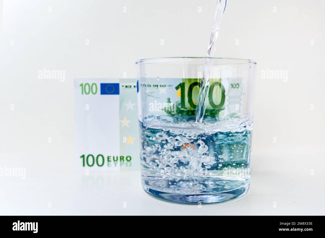 Wasser spritzt aus dem Glas mit Euro-Rechnung Hintergrund im Konzept des Wirtschaftswachstums Stockfoto