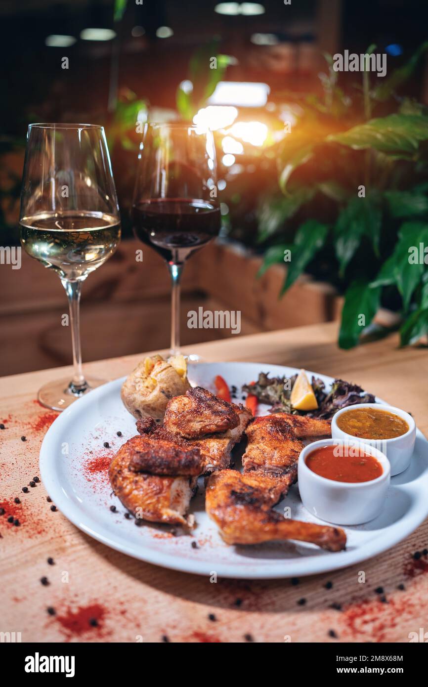Georgische Küche Gericht gebratenes Huhn Tapaka auf dem Teller und Wein im Restaurant Stockfoto