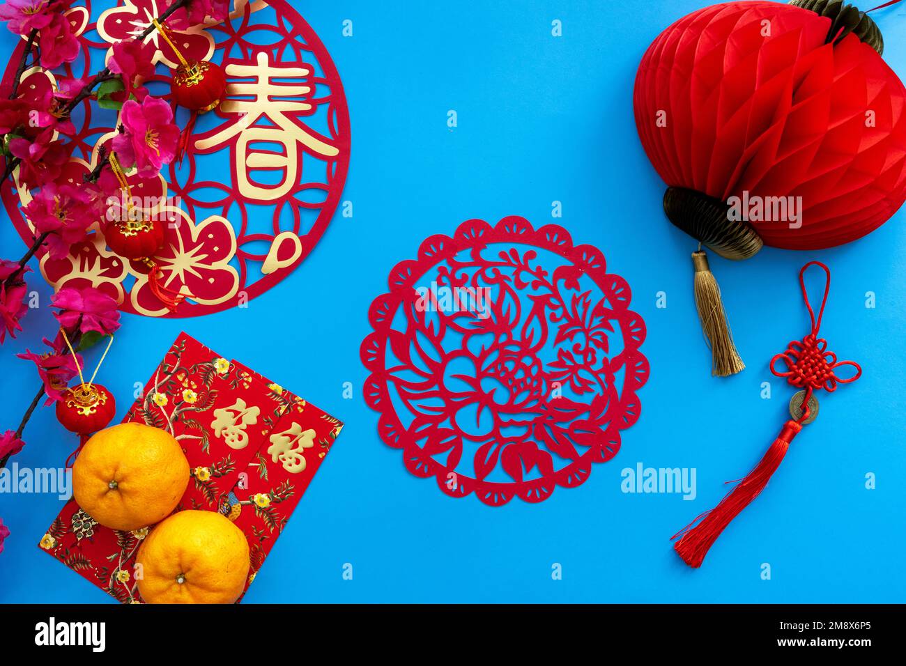 Dekoration im chinesischen Neujahrsmond auf blauem Hintergrund. Flaches Lagekonzept mit Mandarinorange, rotem Umschlag und festlicher Dekoration. Stockfoto