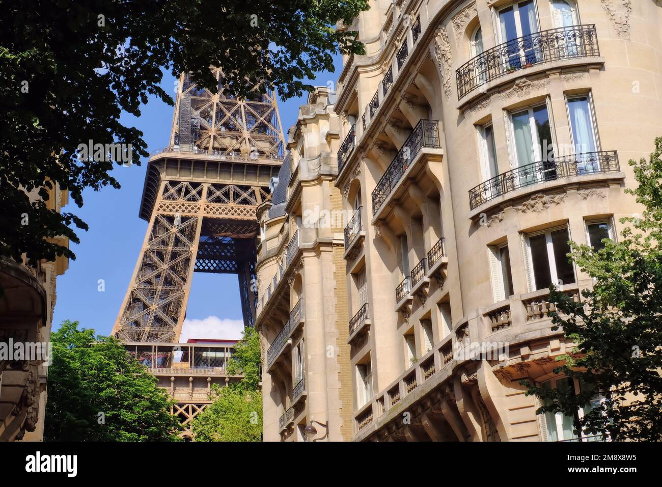 Paris: Nahaufnahme der hübschen Rue Buenos-Ayres mit einem Teil des Eifelturms hinter sonnigen Gebäuden in Paris, Frankreich Stockfoto