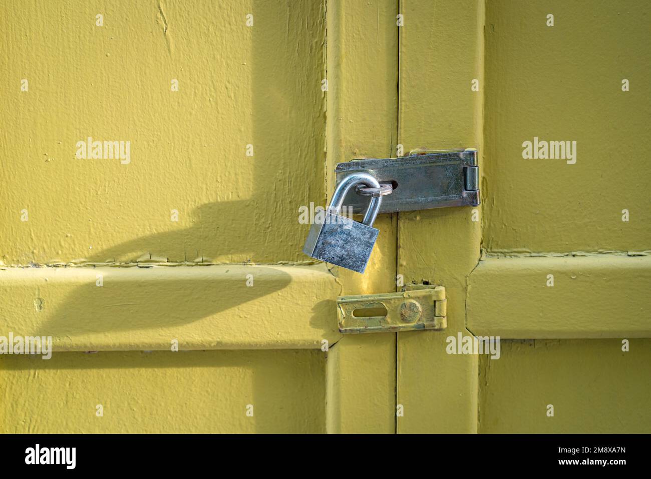 Gelbe Holztür mit Vorhängeschloss geschlossen. Sicherheitskonzept, Kopierraum. Stockfoto
