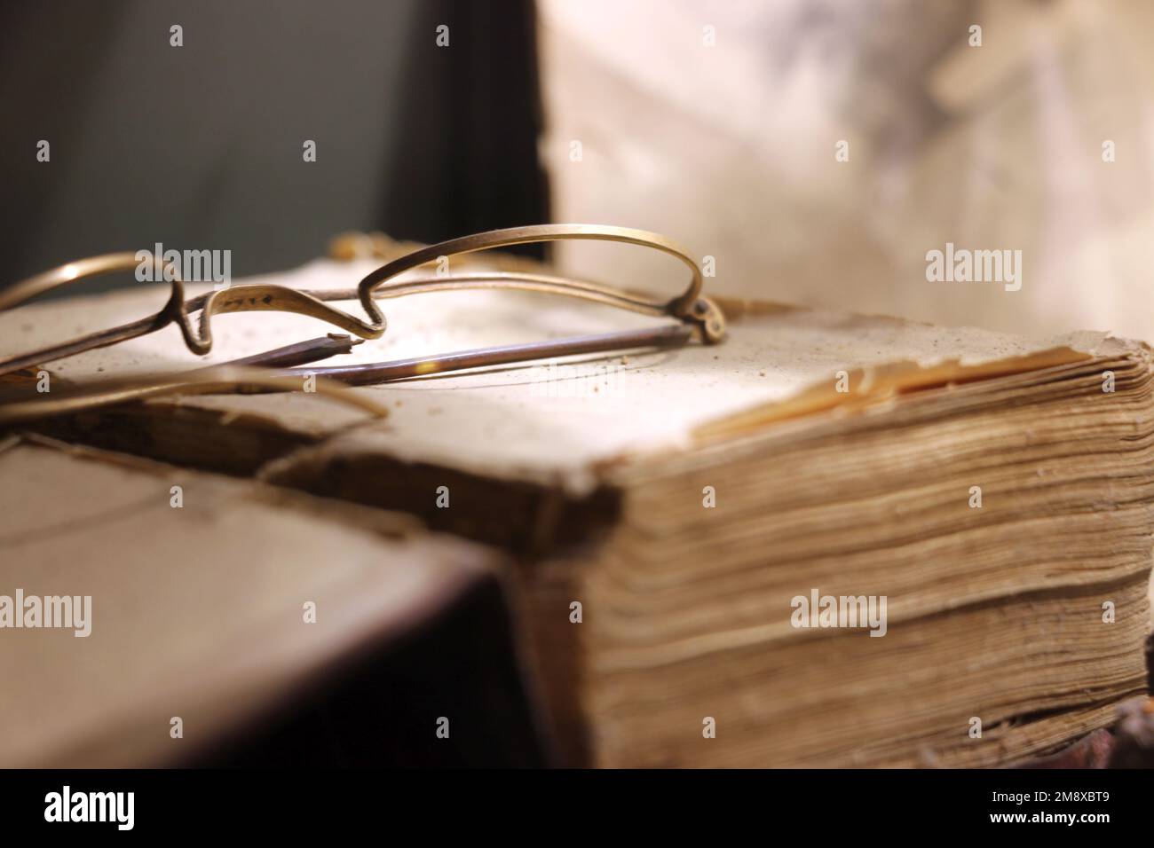 Antike Brille mit Drahtrand, die auf einem alten Buch ruht. Stockfoto