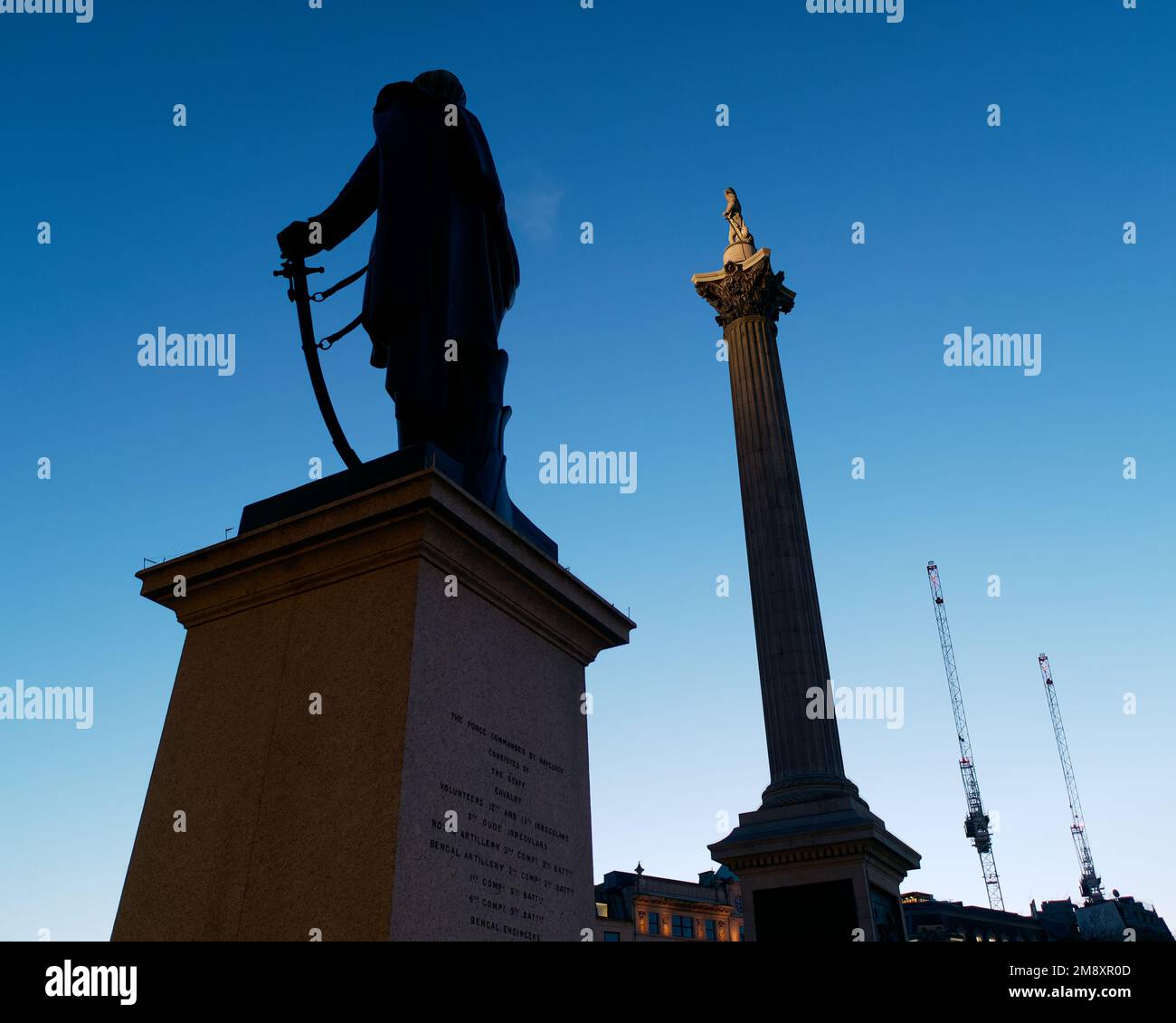 Sir Henry Havelock Statue in Silhouette und Nelsons Column teilweise beleuchtet. Abenddämmerung am Trafalgar Square, London Stockfoto