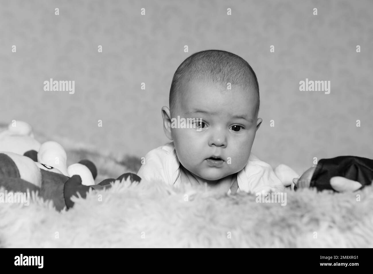 Schwarz-Weiß-Porträt eines kleinen Jungen, der auf dem Bett liegt Stockfoto