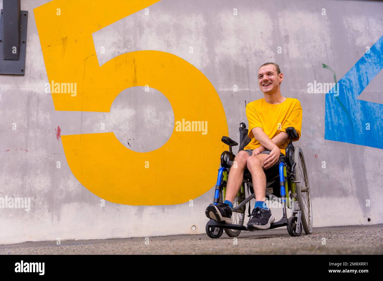 Eine behinderte Person in einem öffentlichen Park mit Nummern an der Wand in einem Rollstuhl Stockfoto