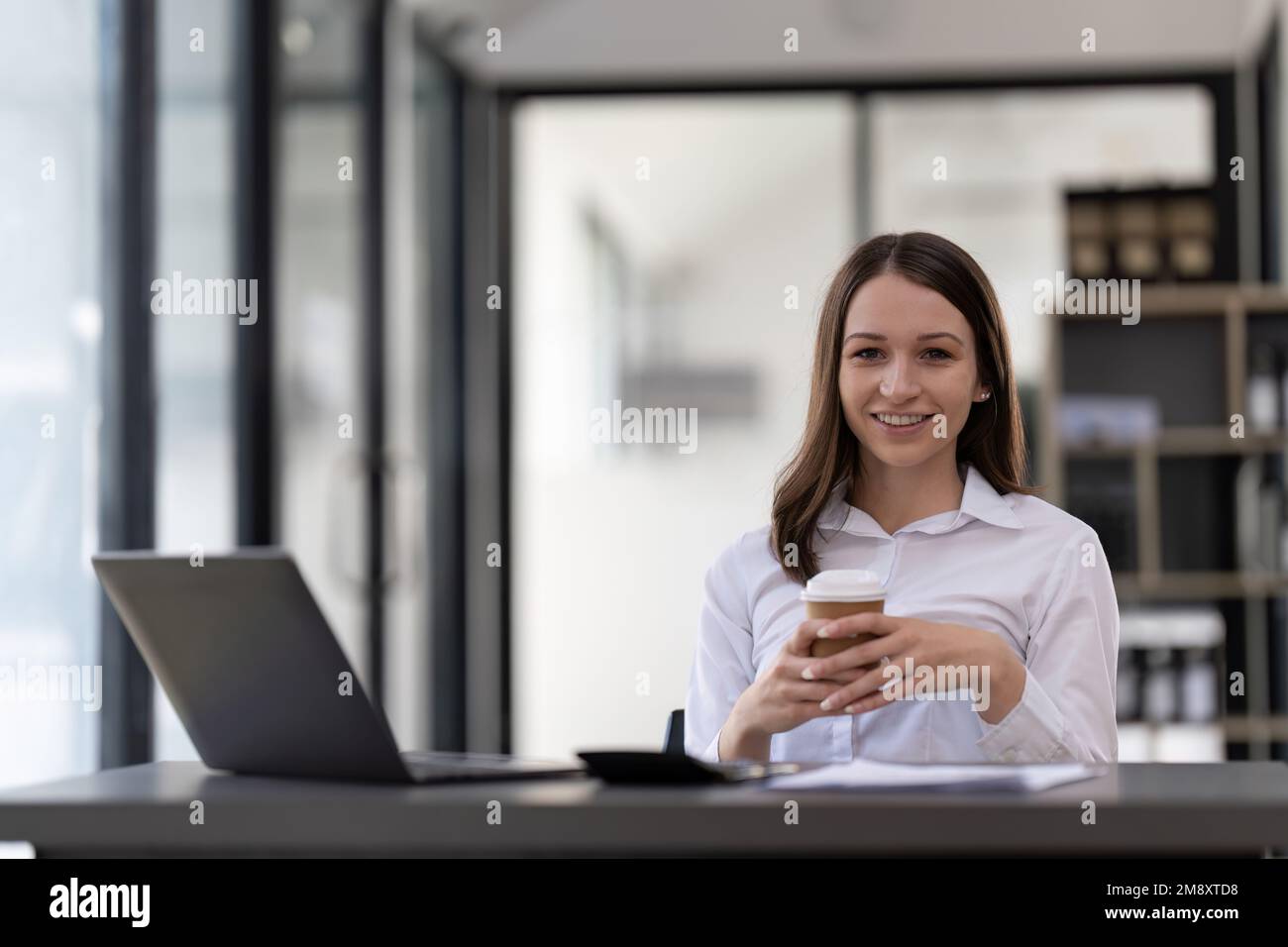Porträt selbstbewusste Geschäftsfrau, die an ihrem Arbeitsplatz in einem modernen Büro mit einem Notebook arbeitet. Stockfoto