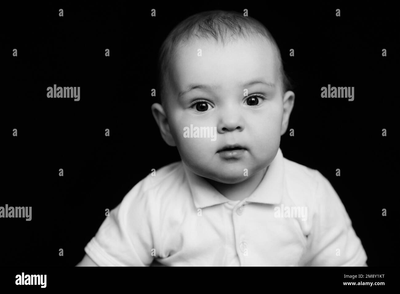 Schwarz-weißes Porträt eines lustigen, süßen kleinen Kindes. Ein weißer Junge, der in die Kamera schaut Stockfoto