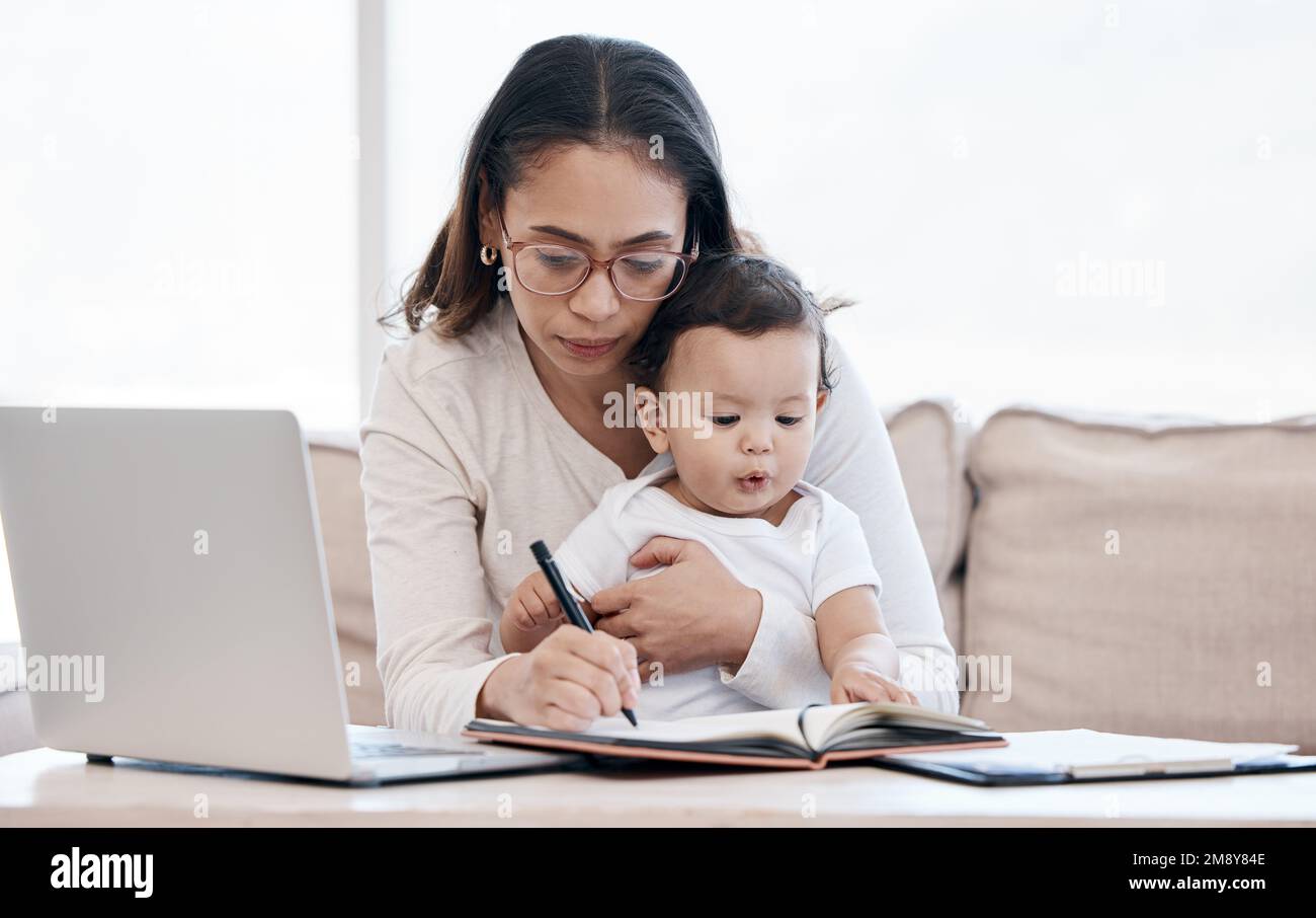 Mom ist heute sehr ernst. Eine junge Mutter, die sich um ihr kleines Mädchen kümmert, während sie von zu Hause aus arbeitet. Stockfoto