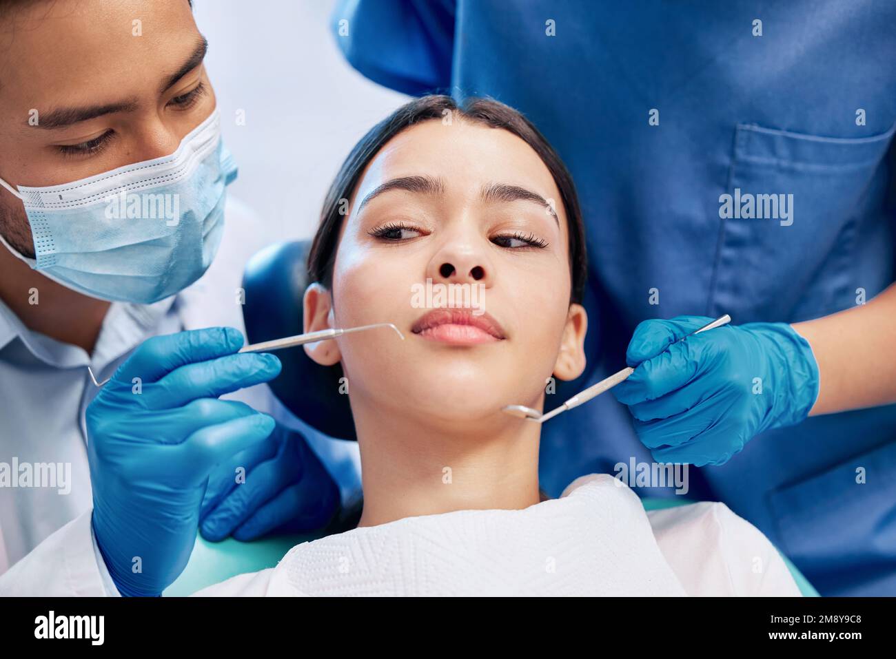 Ich bin mir bei all dem nicht sicher. Eine junge Frau, die in ihrer Zahnarztpraxis unsicher aussieht. Stockfoto