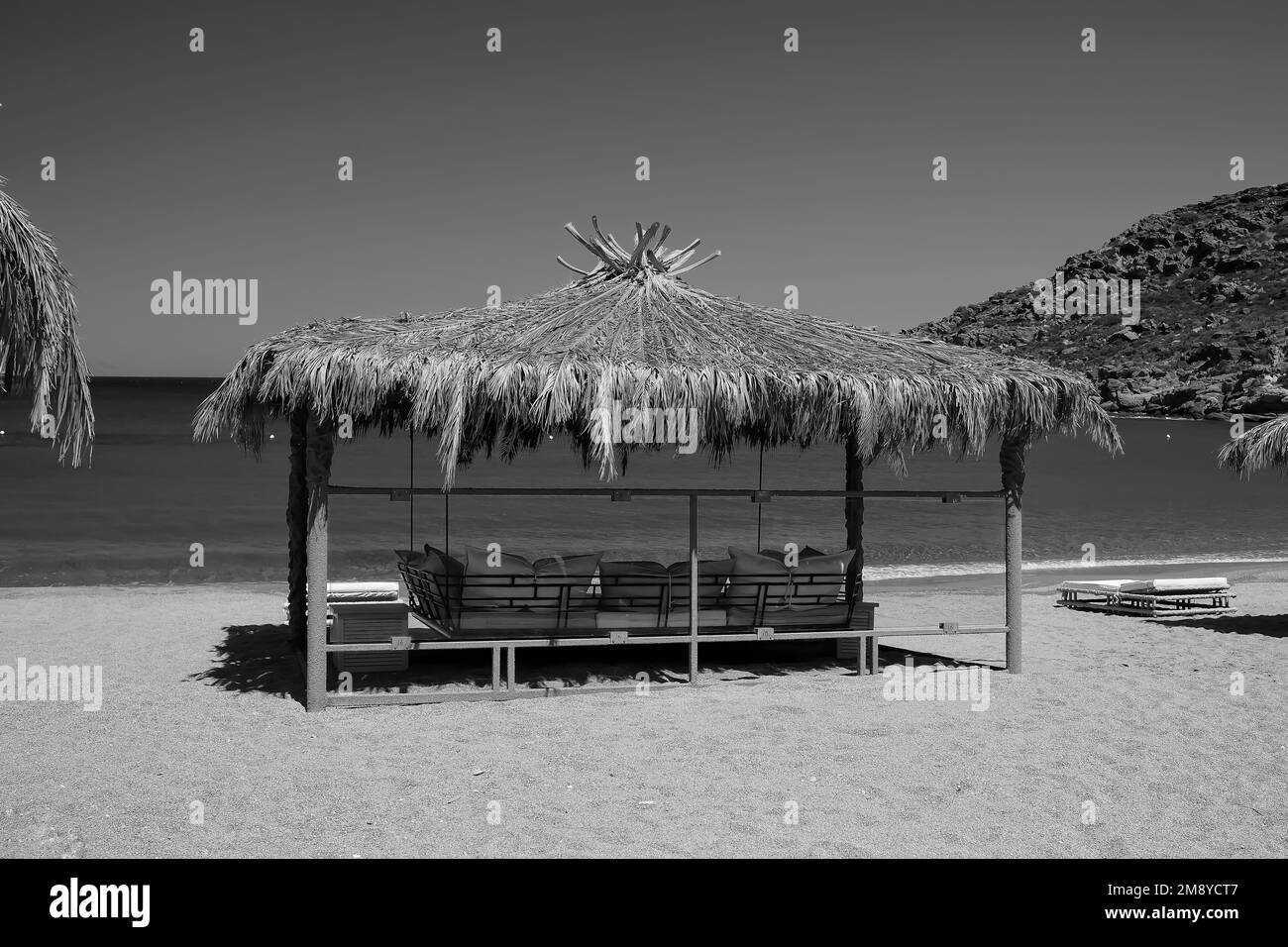 Blick auf eine riesige, luxuriöse Sonnenliege am Papas Beach in iOS Greece in Schwarz und Weiß Stockfoto