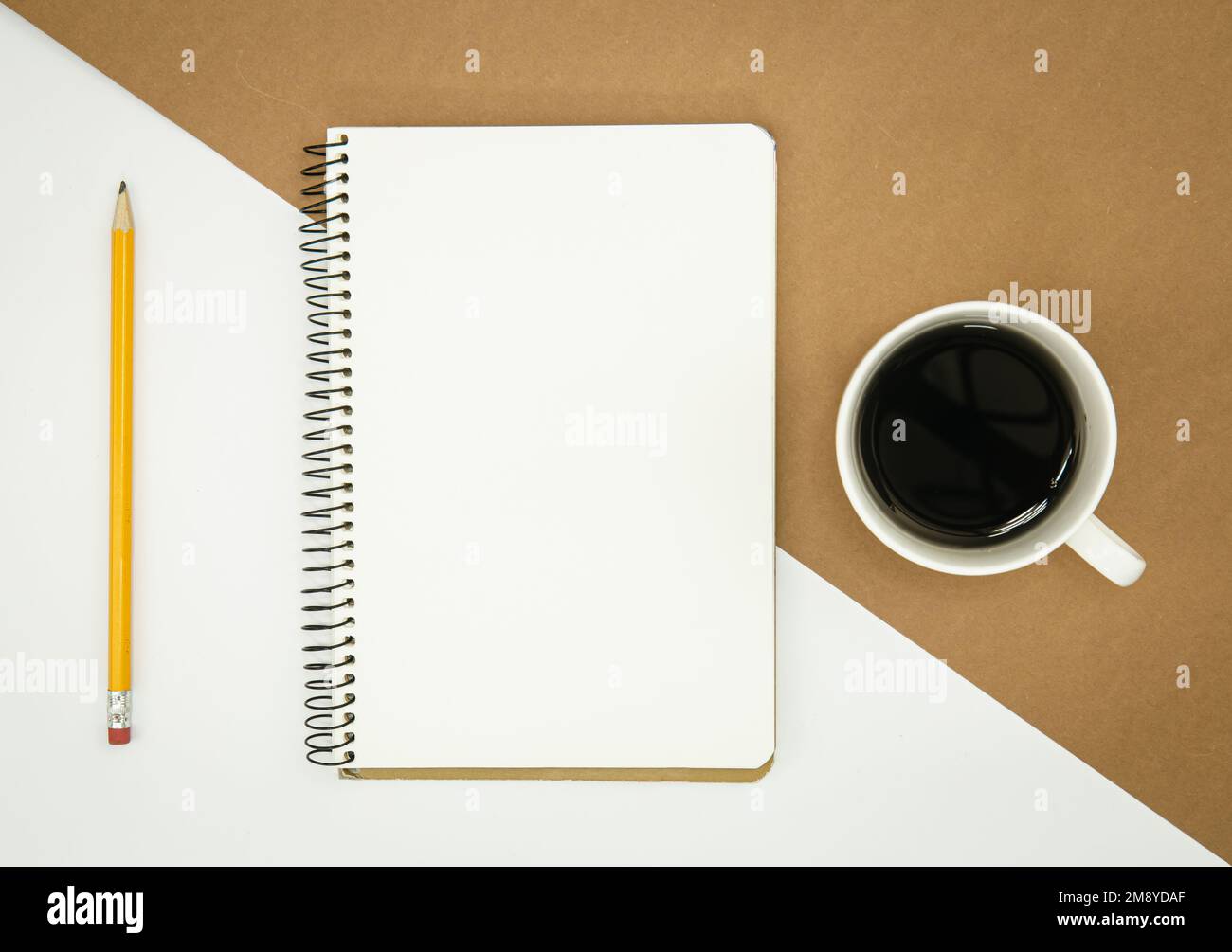 Unbeschrifteter Notizblock, Kaffeetasse und Bleistift, flach liegend. Stockfoto