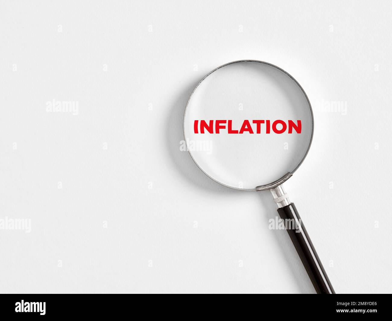 Inflation und Finanzkrisenkonzept. Durch eine Lupe wird das Wort Inflation auf weißem Hintergrund vergrößert. Stockfoto