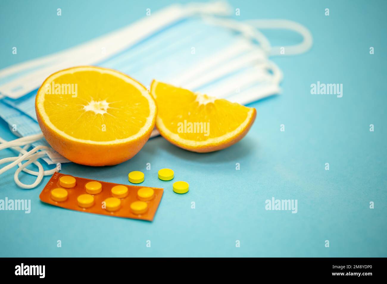 Orangenfrucht, Pillen und Masken auf blauem Hintergrund. Stockfoto
