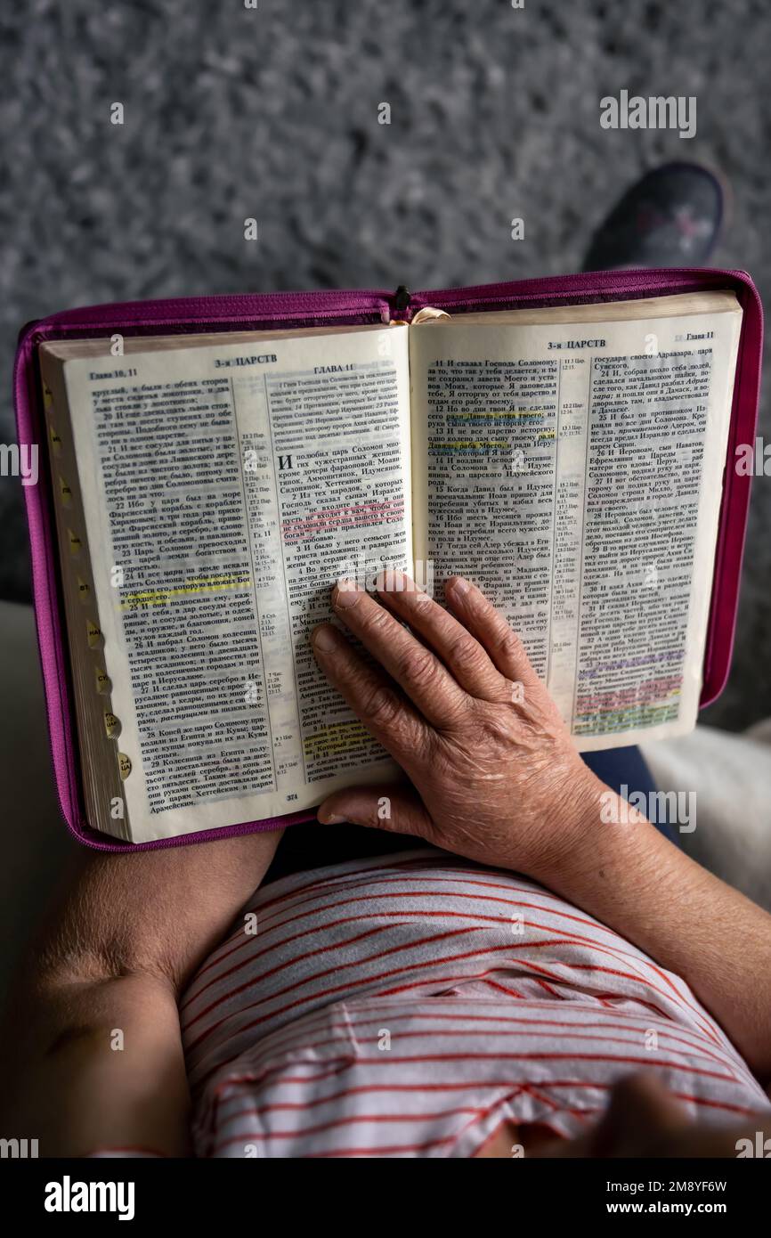 Eine alte Frau liest die Bibel, die Hände sind dicht. Stockfoto