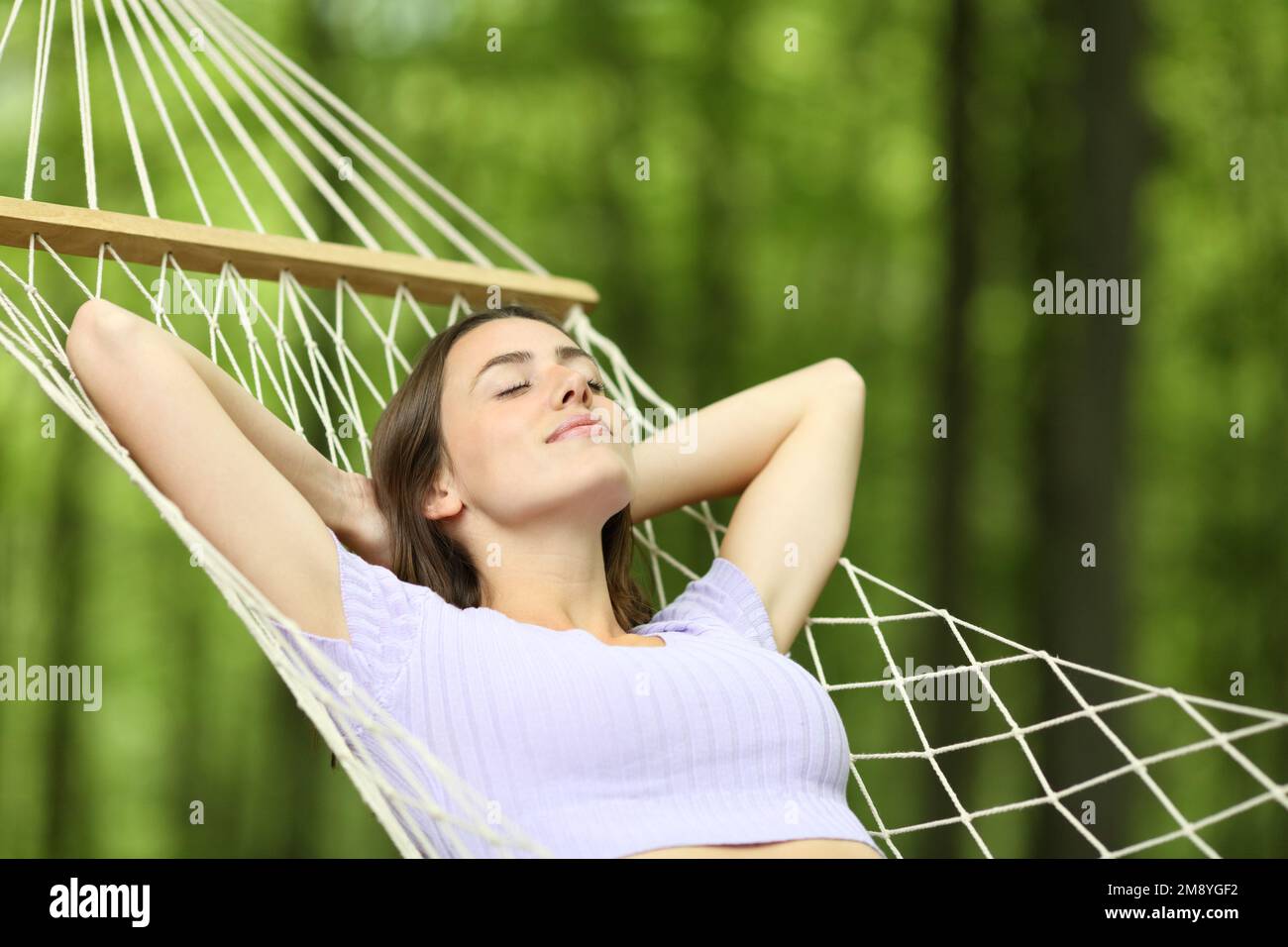 Eine Frau, die sich in einer Hängematte in einem Wald ausruht Stockfoto