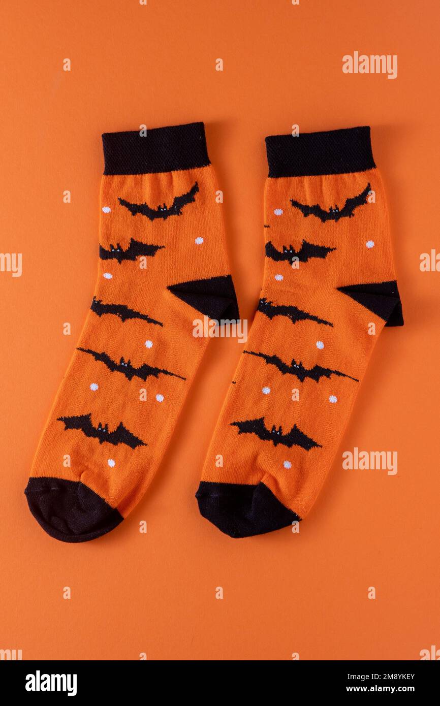 Orangefarbene Socken mit Fledermäusen. Kleidungskostüm für Halloween-Party. Fröhliche, bunte Socken, Draufsicht. Stockfoto
