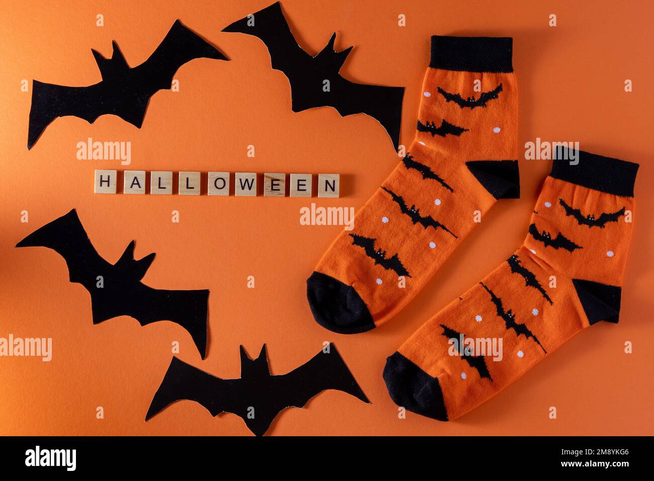 Orangefarbene Socken mit Fledermäusen. Kleidungskostüm für Halloween-Party. Fröhliche, bunte Socken, Draufsicht. Phrase in Holzbuchstaben. - Ja, Richtig. Stockfoto