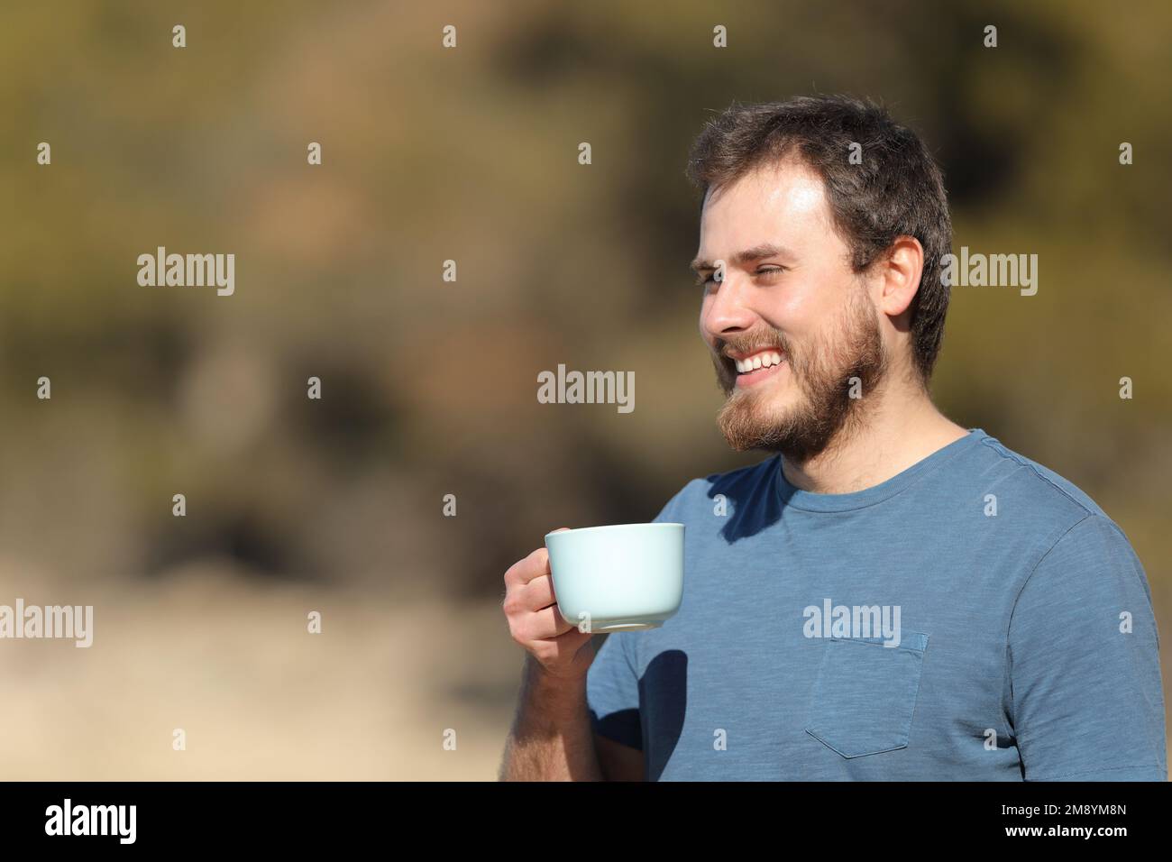 Glücklicher Mann, der eine Kaffeetasse hält und die Aussicht auf die Natur mit Kopierraum betrachtet Stockfoto
