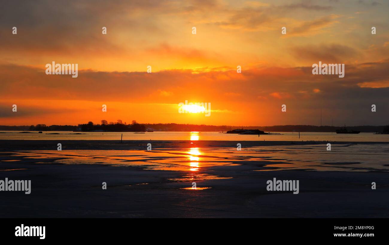 Feuriger Sonnenaufgang über teilweise gefrorenem Meer - Eis brennt. Helsinki, Finnland. März 2021. Stockfoto