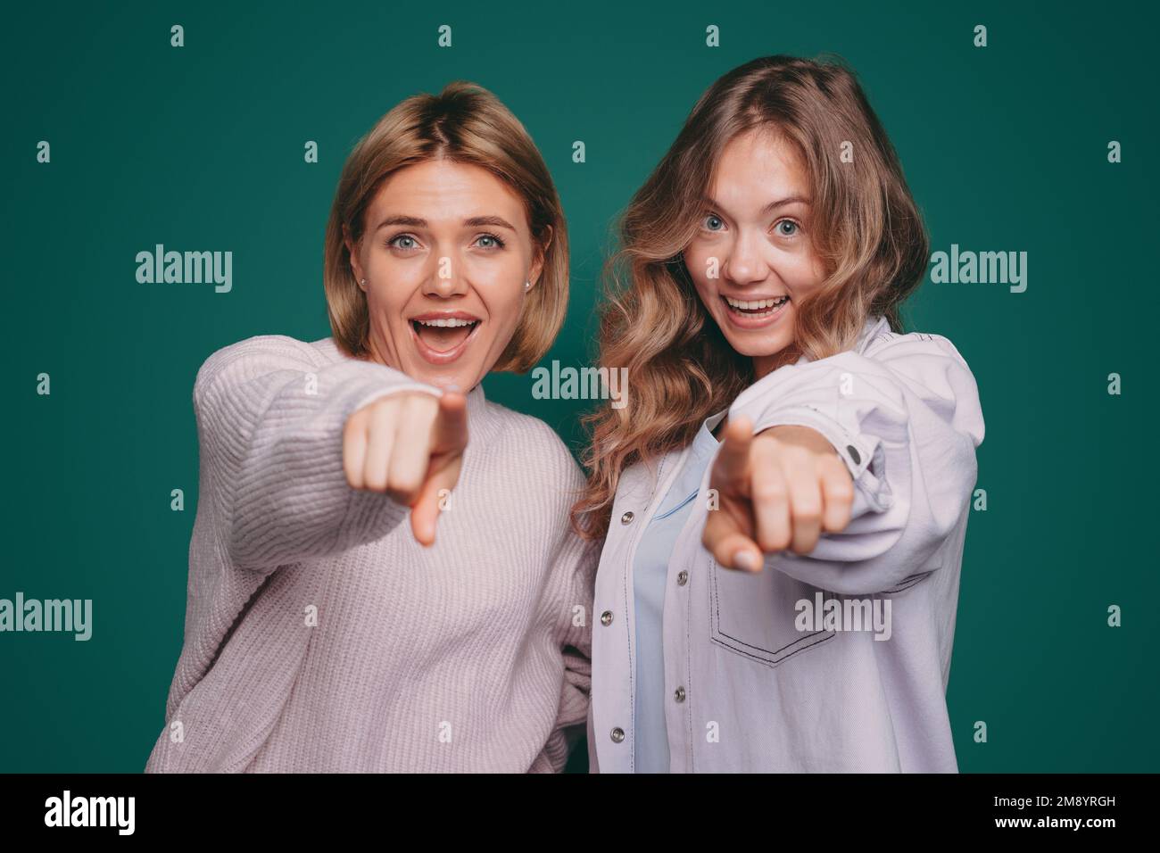Ein Bild von zwei Schwestern, die laut lachen und mit dem Finger auf die Kamera zeigen. Genießen Sie jeden Moment. Stockfoto