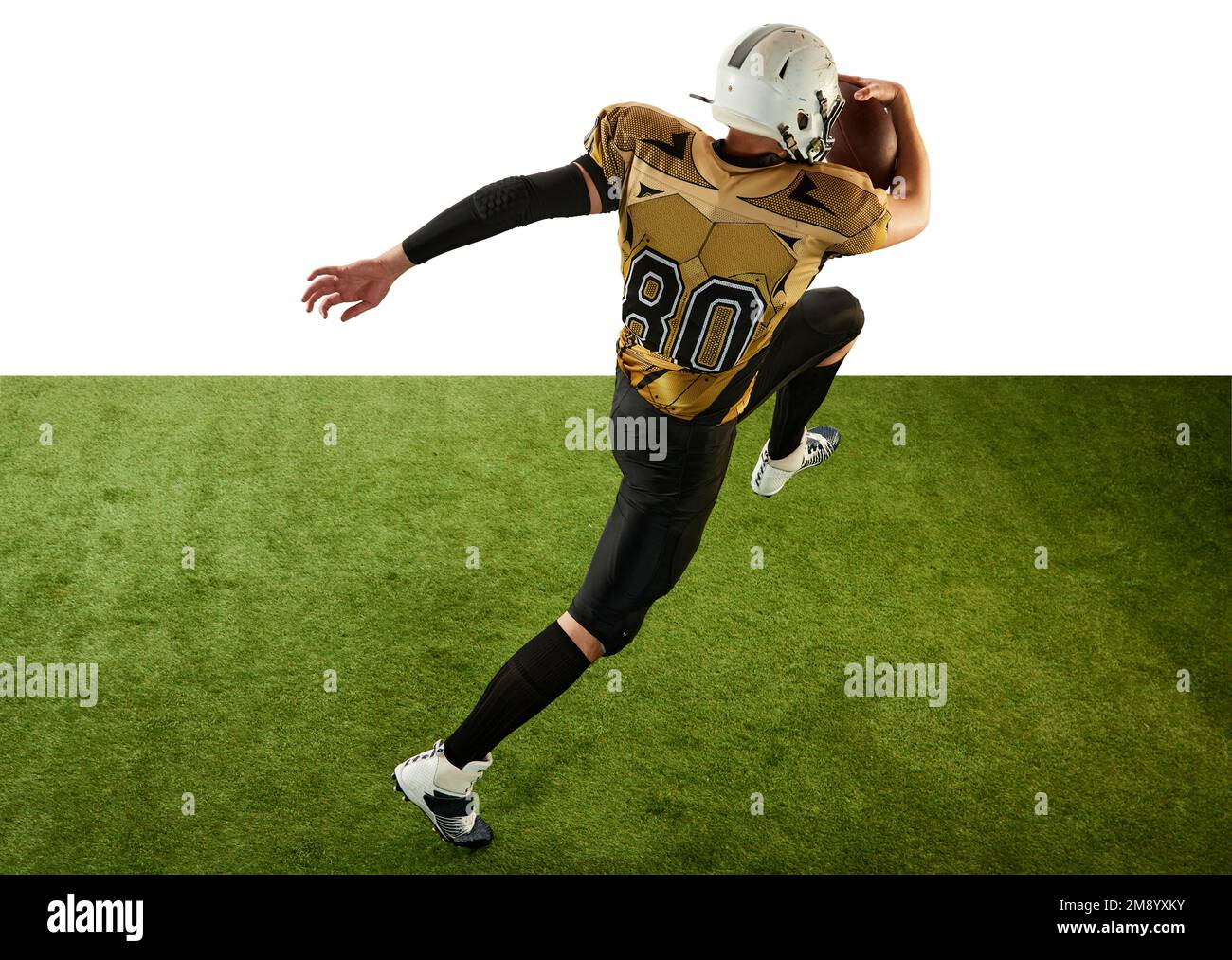 Mann, professioneller american Football-Spieler in Bewegung, Training, mit Ball auf weißem Studiohintergrund mit grünem Grasboden laufen. Konzept von Stockfoto