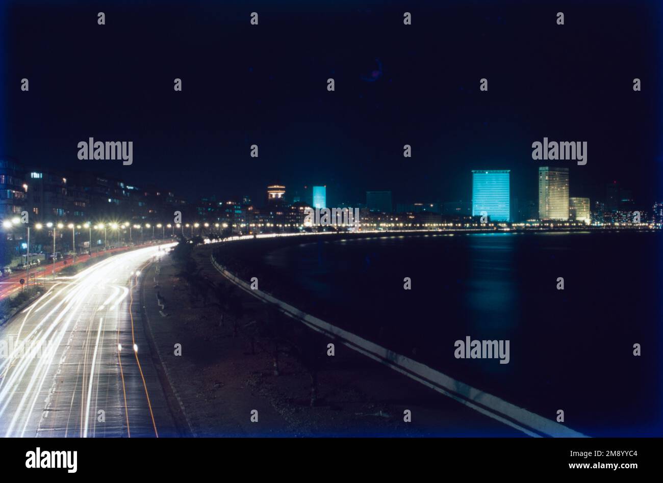 Der Marine Drive ist eine 3 Kilometer lange Promenade entlang der Netaji Subhash Chandra Bose Road in Mumbai, Indien. Die Straße und die Promenade wurden von Pallonji Mistry gebaut. Es ist eine C-förmige, sechsspurige Betonstraße entlang der Küste einer natürlichen Bucht. Diese berühmte Straße grenzt an das Arabische Meer und ist ein beliebter Ort, um Sonnenuntergänge zu beobachten, und sie ist wunderschön, wenn sie nachts beleuchtet ist. Der Marine Drive, eine Strandpromenade, ist ein wichtiger Erholungs- und Touristenattraktion in Mumbai. Stockfoto