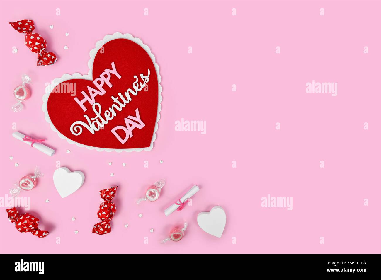 Valentinstag-Flachbett mit Herz und Text „Happy Valentine's Day“, Süßigkeiten und Herzverzierungen auf pinkfarbenem Hintergrund mit Kopierbereich Stockfoto