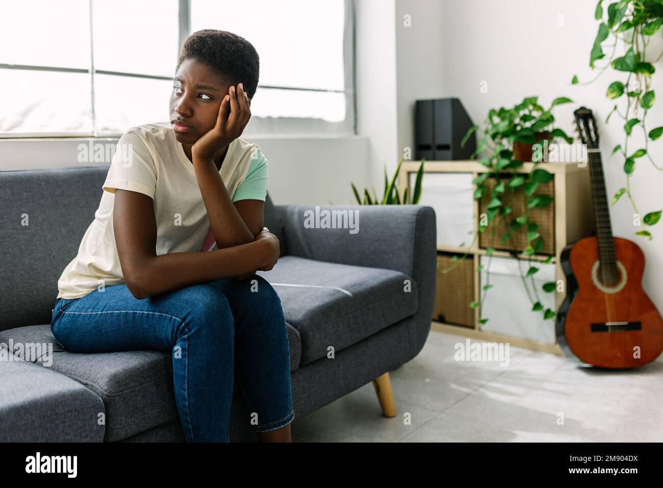 Junge schwarze Frau, die auf dem Sofa sitzt und sich Sorgen um persönliche Probleme macht Stockfoto
