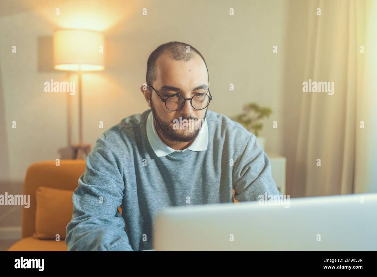 Männlicher Freiberufler oder IT-Code-Entwickler, der auf einem Laptop arbeitet. Programmierer oder junger Geschäftsmann im Heimbüro, entfernter Job. Stockfoto
